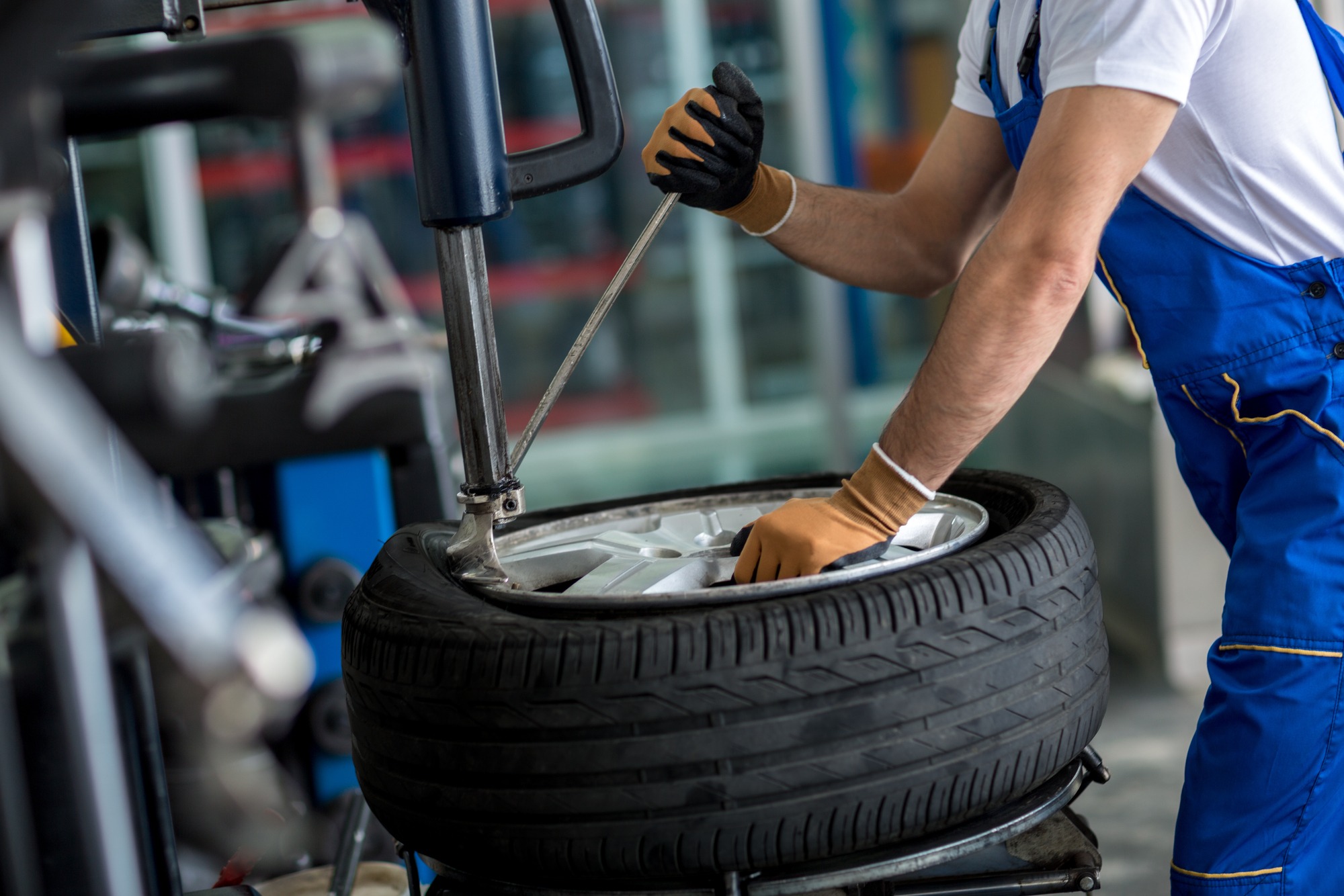 A mechanic uses a tire machine to mount a tire onto a wheel in an automotive workshop, demonstrating tire installation procedures.